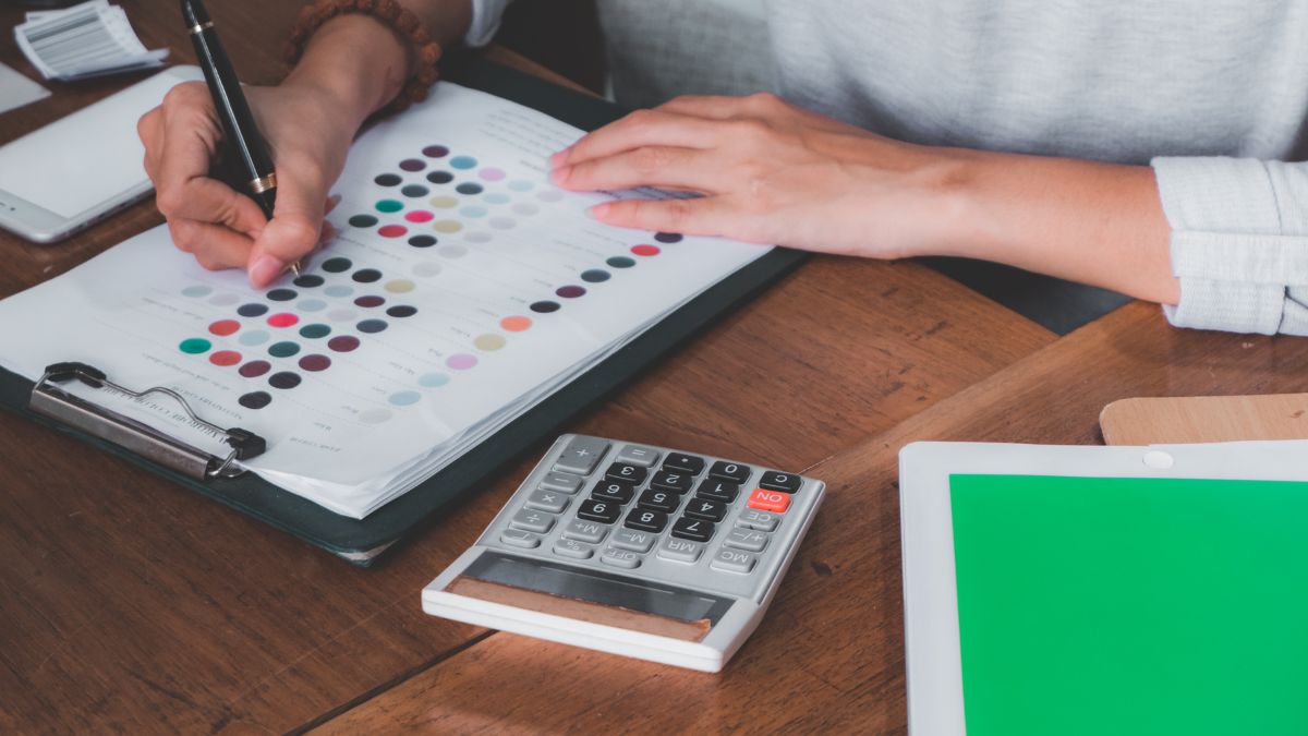 Un indépendant gère ses factures sur une table en bois avec une feuille et une calculatrice.